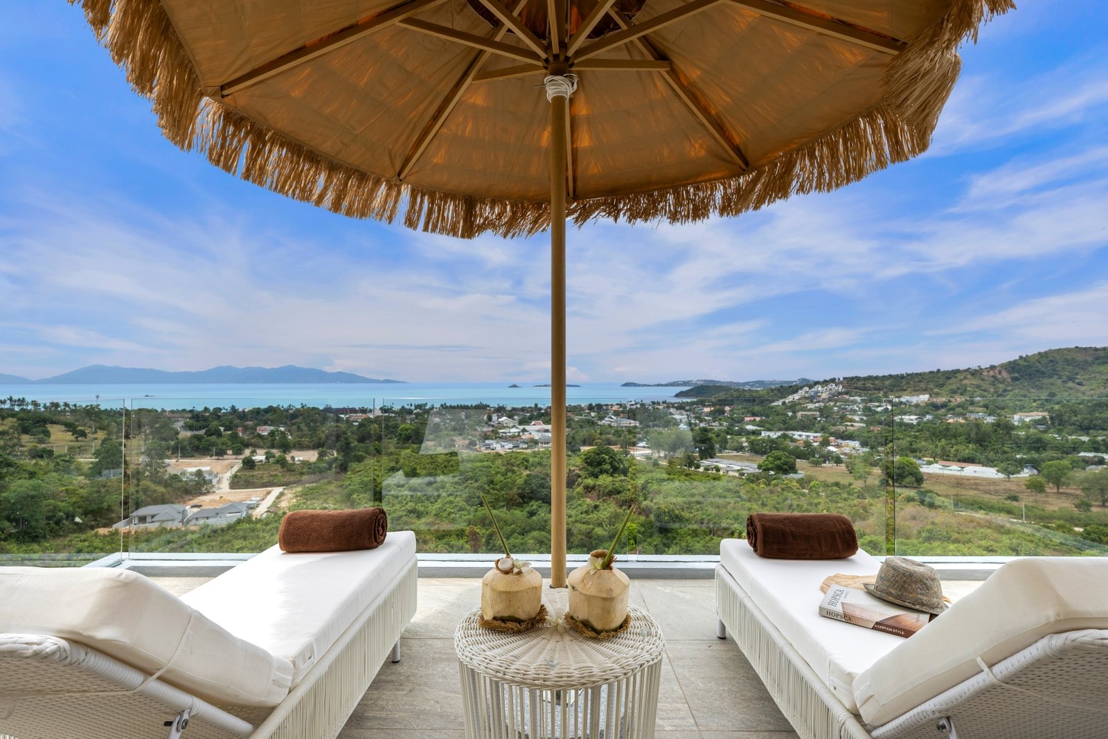Rooftop loungers under the fringed umbrella, sea beyond